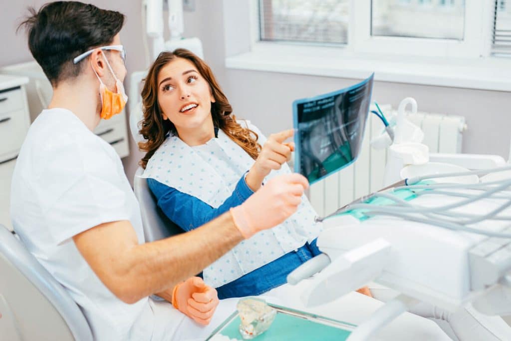 Female patient asking male dentist about x-ray during dental exam