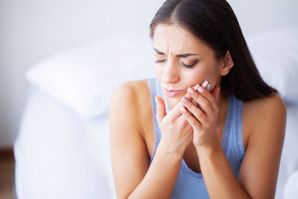 a woman holds her jaw