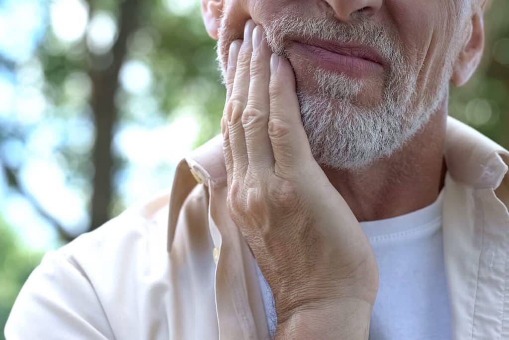 a man holds his jaw